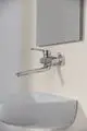 Wandarmatur in Chrom von Ideal Standard, ausgestattet mit einem langen Auslauf und S-Anschlüssen, montiert über einem Waschbecken an einer hellen Wand.